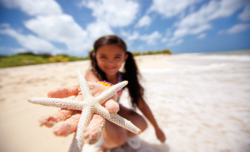 Kind met zeester op het strand 