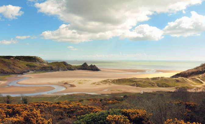 Een strand met een rivier in Wales